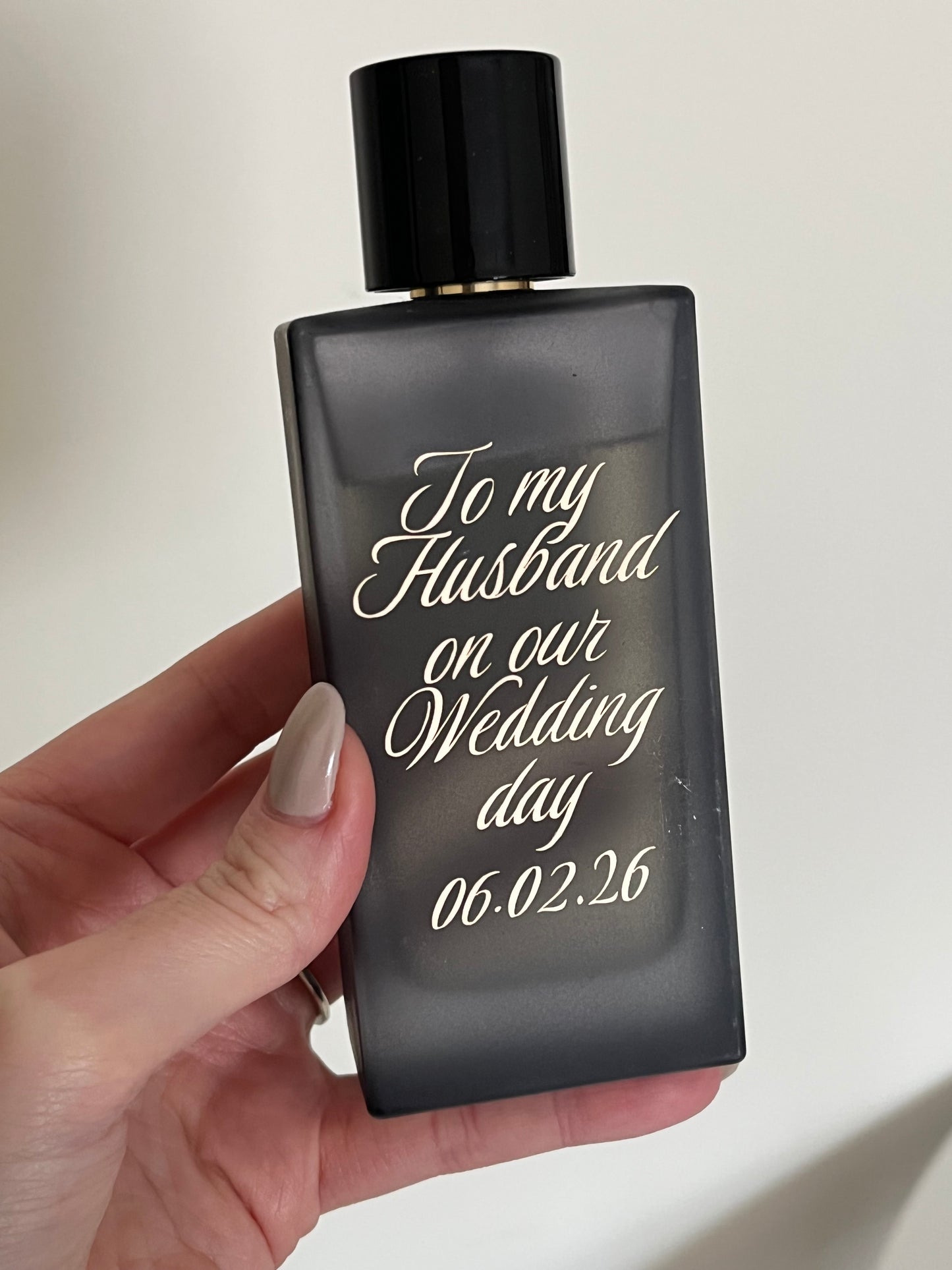Personalized perfume bottle held by a hand with a light background