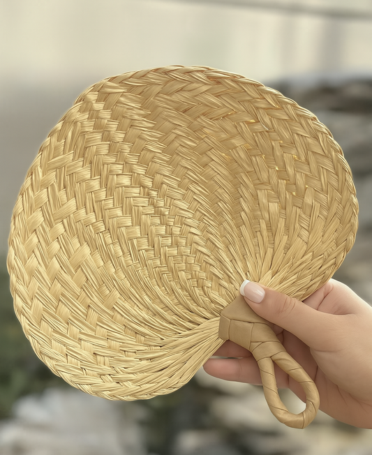 Hand holding a woven straw rattan fan for weddings